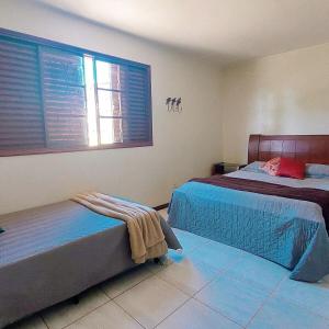 a bedroom with two beds and a window with blinds at Complexo Alpes do Cerrado in Sobradinho