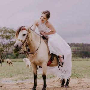 a woman in a white dress riding a horse at Complexo Alpes do Cerrado in Sobradinho