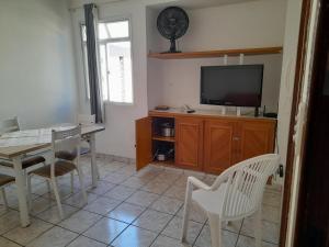 ein Wohnzimmer mit einem TV, einem Tisch und Stühlen in der Unterkunft Apartamento Temporada Praia do Morro in Guarapari
