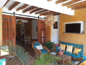 a living room with blue chairs and a television at Casona CHARA in Barichara