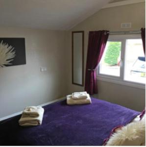 a bedroom with a purple bed with two towels on it at Peregrine Lodge - idillic Cornwall retreat in Liskeard