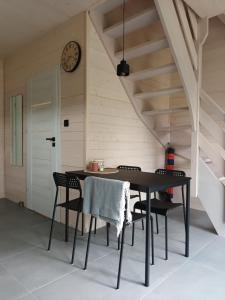 a dining room table with chairs and a clock on the wall at Zakątek na Ptasiej in Sasino