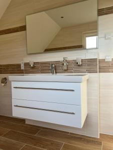 a bathroom with a sink and a mirror at Ferienhaus Svantovit - exklusives Ferienhaus mit Sauna, Whirlpool und Kamin in Putgarten