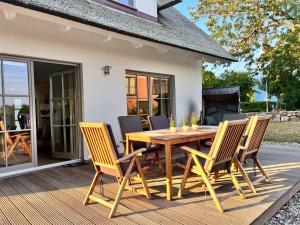 una mesa de madera y sillas en una terraza en Ferienhaus Svantovit - exklusives Ferienhaus mit Sauna, Whirlpool und Kamin, en Putgarten