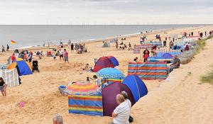 a group of people on a beach with umbrellas at Hollie’s Hemsby holidays - static caravan in Hemsby