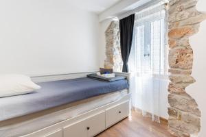 uma cama num quarto com uma parede de pedra em Apartments Rose em Cres