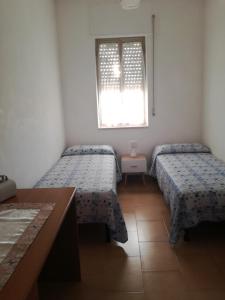 Dos camas en una habitación pequeña con ventana. en Villa Leo, en Ostuni