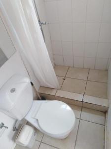 a bathroom with a white toilet and a tiled floor at Camping Las Machas in Bahia Inglesa