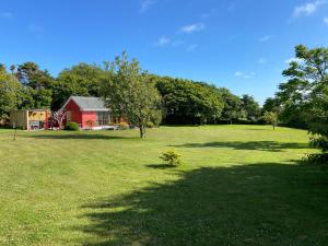 a large green field with a red barn and trees at Meadowside Lodge with Hot Tub in Truro