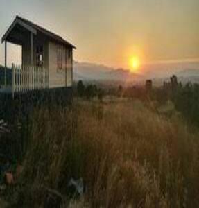 uma casa num campo com o pôr-do-sol ao fundo em Nutan Vilas Mahadik Paryatan Kendra , Chiplun em Chandoli