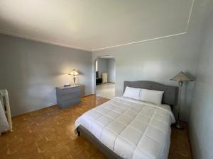 Falls House Downtown Niagara Falls Canada في شلالات نياجارا: غرفة نوم بسرير ابيض ومصباح وممر