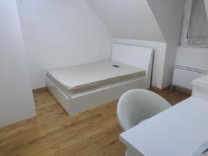 a small white room with a bed and a chair at Chambre privée à Bobigny -salle de bain et toilettes sont commune, -pas de cuisine in Bobigny