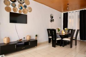 uma sala de jantar com mesa e cadeiras e uma televisão em F&H 2 Bedroom cozy - Kigali apartment unit em Kigali