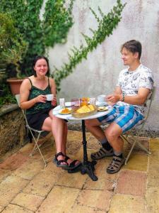 mężczyzna i kobieta siedzący przy stole z jedzeniem w obiekcie La Dilettante w mieście Malause