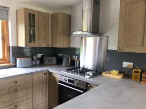a kitchen with wooden cabinets and a stove top oven at Lachie's Cabin in Portree