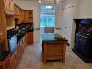 Bratton ClovellyにあるHeadson Farmhouse Longer stay for lessの木製のキャビネットと黒い島のある広いキッチン