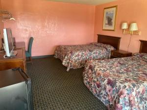 a hotel room with two beds and a desk and a tv at Budget inn in Alma