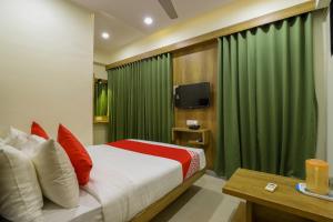 um quarto com uma cama e uma cortina verde em OYO Hotel Shubham Inn em Ahmedabad