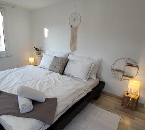 een wit bed met witte kussens en een klok aan de muur bij Sechs Bergspitzen in Ebnat-Kappel