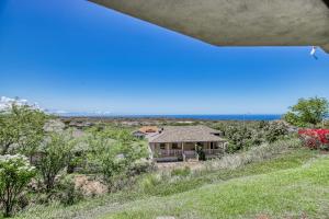 a house on a hill with the ocean in the background at Greens At Waikoloa L101 in Waikoloa Village
