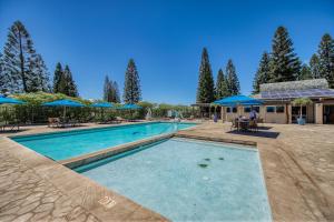 a large swimming pool with blue umbrellas in a yard at Greens At Waikoloa L101 in Waikoloa Village