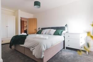 Higham Ferrers的住宿－The Old Band Accommodation，一间卧室配有一张大床和一个白色梳妆台