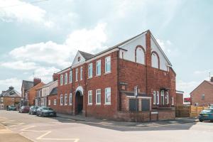 un gran edificio de ladrillo con una cruz en la parte delantera en The Old Band Accommodation en Higham Ferrers