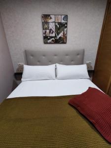Un dormitorio con una gran cama blanca con una manta. en La Dorada, en Boiro