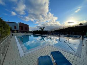 a large swimming pool with two blue chairs in it at Tenerife Family Home in Santa Úrsula