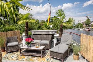 eine Terrasse mit Stühlen, einem Tisch und Wasser in der Unterkunft Schiffsherberge Pöppelmann in Dresden