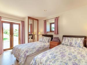 a bedroom with two beds and a window at Routster Cottage in Giggleswick
