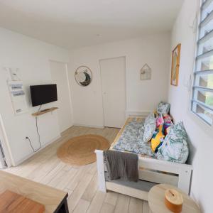 a small white room with a bed and a tv at Les Vanniers: Papaye - KARITÉ in Baie-Mahault