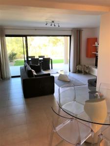 ein Wohnzimmer mit einem Sofa und einem Glastisch in der Unterkunft A SUARA- CORSE- APPARTEMENT 2 chambres 5 à 7 pers, jardin et piscine in Porto-Vecchio