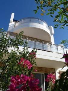 a building with a balcony with flowers on it at Villa Constance, Grapevines Villas in Makry Gialos