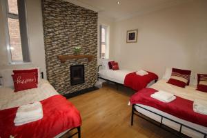 two beds in a room with a brick fireplace at St Ann's House in Rotherham