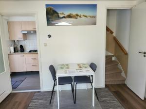 a small white table in a kitchen with two chairs at FlipFlop in Noordwijk aan Zee