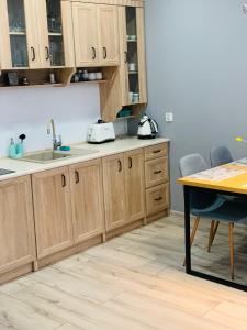 a kitchen with wooden cabinets and a sink and a table at Apartament Champion in Gorzów Wielkopolski