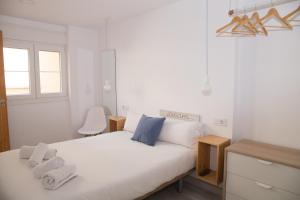 a bedroom with a white bed with towels on it at The Nomad Hostel&Pension in Seville