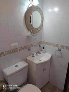 y baño con aseo, lavabo y espejo. en Mediterráneo Cabañas en Chascomús