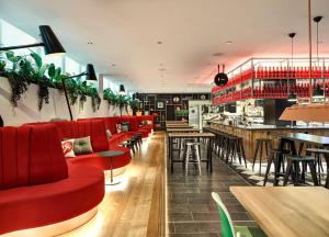 restauracja z czerwonymi miejscami siedzącymi i barem w obiekcie citizenM London Victoria Station w Londynie
