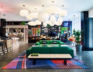 a living room with a green couch and a table at citizenM London Victoria Station in London