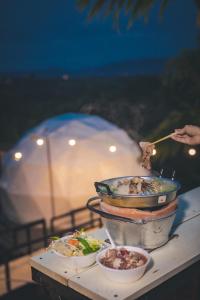 a table with a pot of food and a bowl of food at นรดีฮิวล์ รีสอร์ต เขาแผงม้า วังน้ำเขียว in Ban Sap Bon