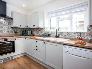 a kitchen with white cabinets and a sink and a window at HONEYBROOK - Cosey detached home, modern, spacious in Torquay
