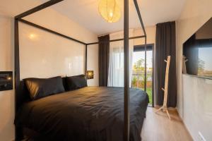 a bedroom with a black canopy bed with a window at LDM Appartements Marrakech in Marrakech