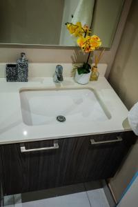 a bathroom sink with a vase of flowers on it at 703 Menlyn Maine Residences, The Trilogy in Pretoria