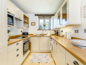 cocina con armarios blancos y encimera de madera en Cottage Anton, en Fylingdales