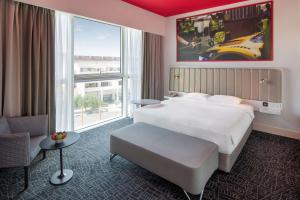 ドバイにあるPark Inn by Radisson Dubai Motor Cityのベッドと大きな窓が備わるホテルルームです。