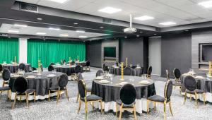 a conference room with tables and chairs and a screen at Park Inn by Radisson Polokwane in Polokwane