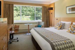 ストラトフォード・アポン・エイボンにあるThe Welcombe Golf & Spa Hotelのベッド、デスク、窓が備わるホテルルームです。