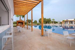 een patio met tafels en stoelen naast een zwembad bij Radisson Blu Resort, Saidia Garden in Saidia 